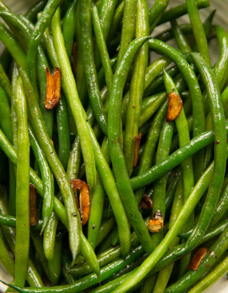 overhead shot of green beans in bowl with garlic chips on top