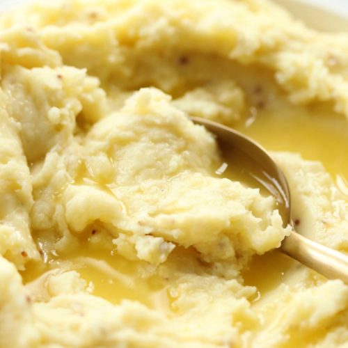 spoon digging into mustard mash with melted butter on top