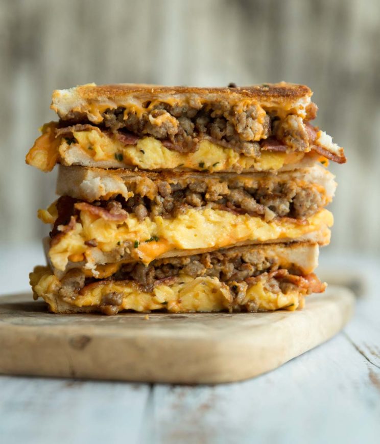 3 breakfast grilled cheese stacked on each other on wooden board