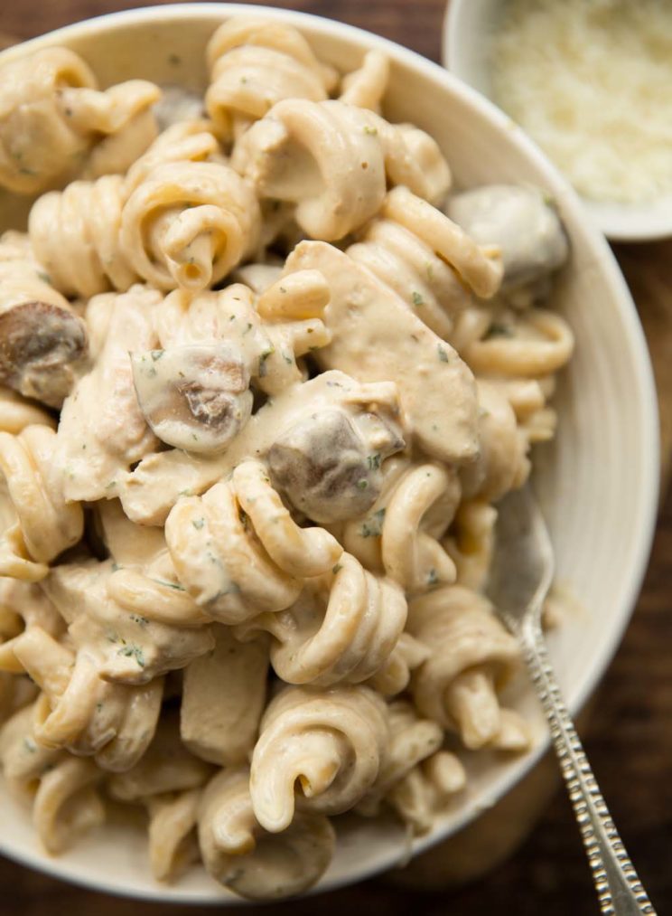 chicken mushroom pasta served in white bowl with fork digging in