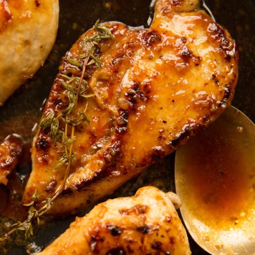 overhead shot of chicken in pan with spoon and sauce