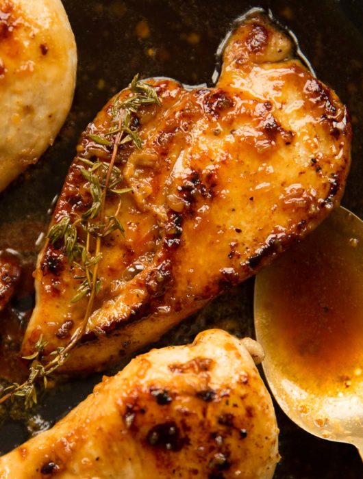 overhead shot of chicken in pan with spoon and sauce