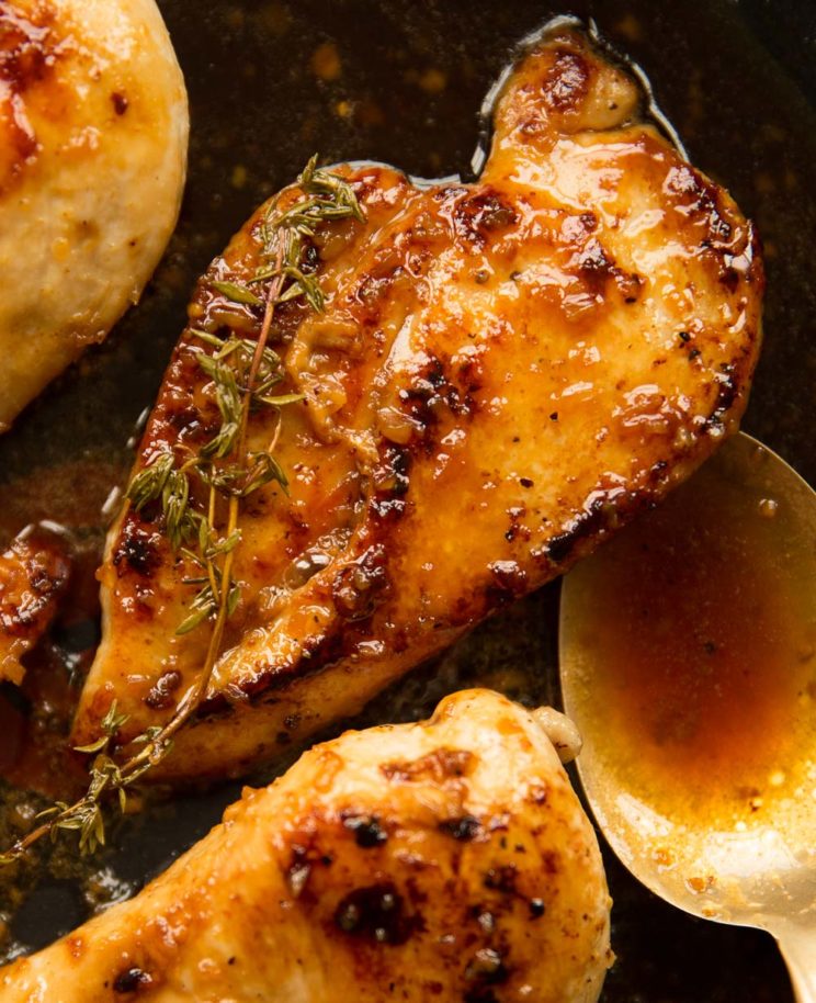 overhead shot of chicken in pan with spoon and sauce