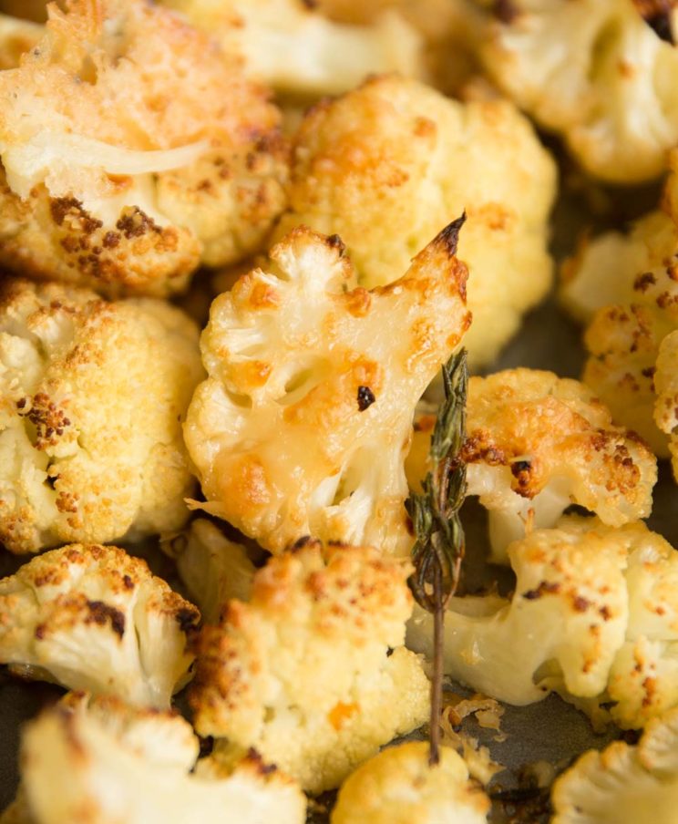 closeup shot of parmesan roasted cauliflower on baking tray with thyme