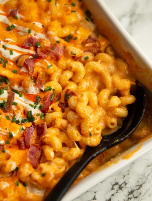 close up shot of serving spoon digging in to baked buffalo chicken mac and cheese fresh out the oven