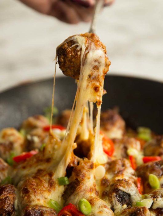 pull meatball out of skillet with fork and cheese dripping down
