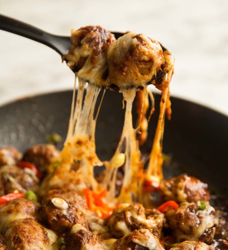 pulling meatballs out of skillet with cheese falling down