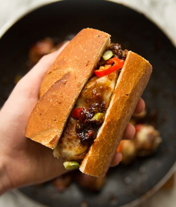 holding meatball sub to camera with skillet blurred in background