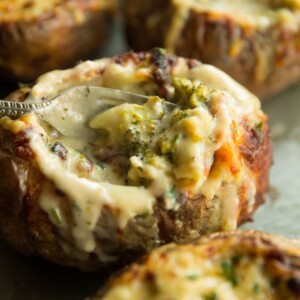 closeup shot of broccoli inside side baked potato with fork digging in