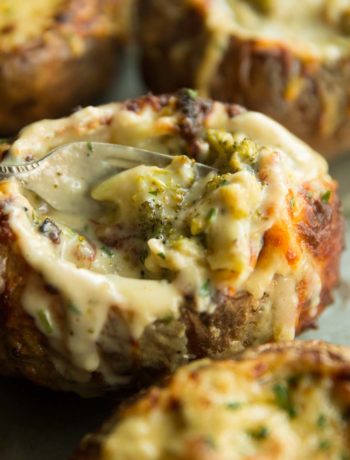 closeup shot of broccoli inside side baked potato with fork digging in