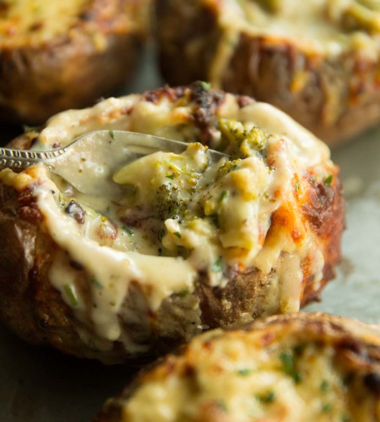 closeup shot of broccoli inside side baked potato with fork digging in