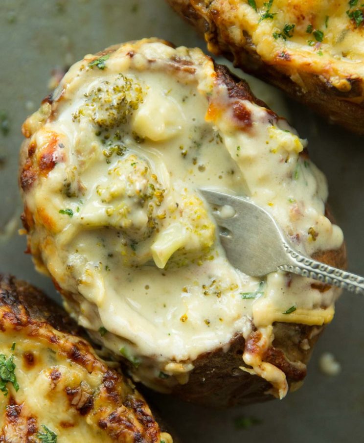 overhead shot of fork digging into broccoli cheese inside potato