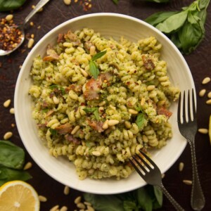 overhead shot of broccoli pesto pasta in white bowl surrounded by ingredients