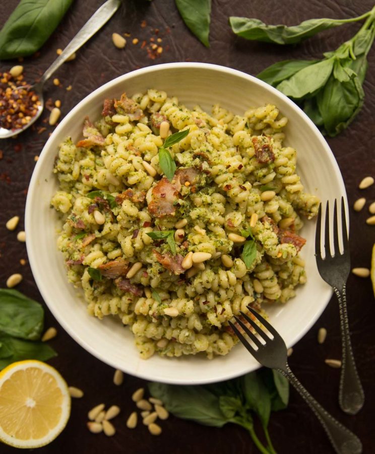 overhead shot of broccoli pesto pasta in white bowl surrounded by ingredients