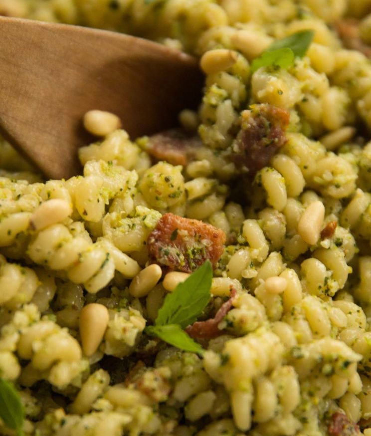 closeup shot of broccoli pesto pasta, focus on slice of bacon