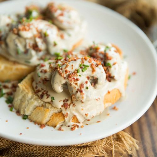creamy mushrooms on two slices of toast with bacon and chives