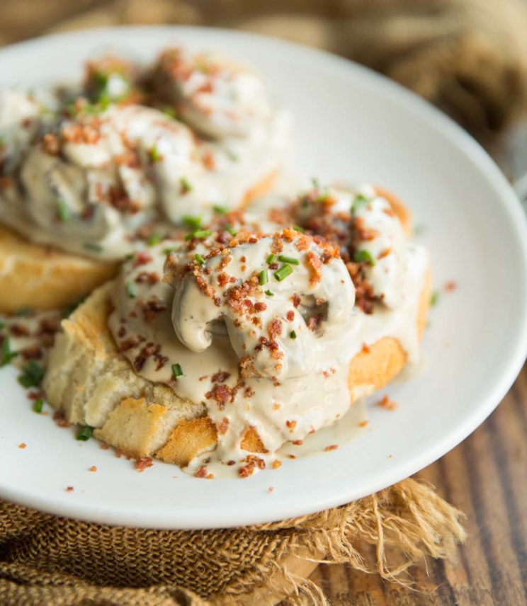 creamy mushrooms on two slices of toast with bacon and chives