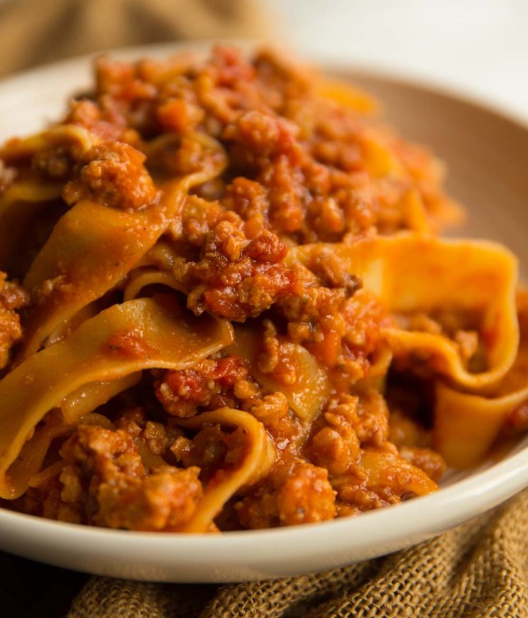 Pappardelle Ragu with Sausage in white bowl placed on chopping board