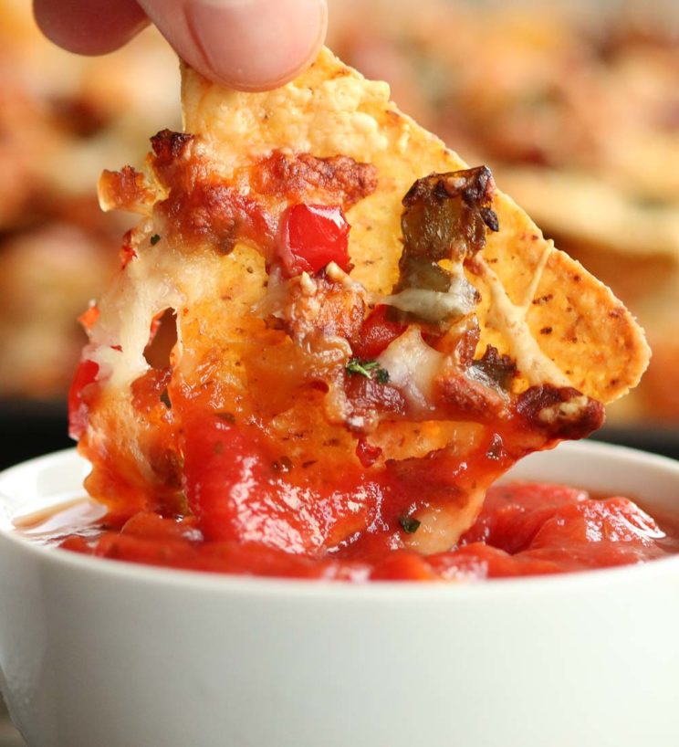 dipping chicken fajita nacho into tomato salsa