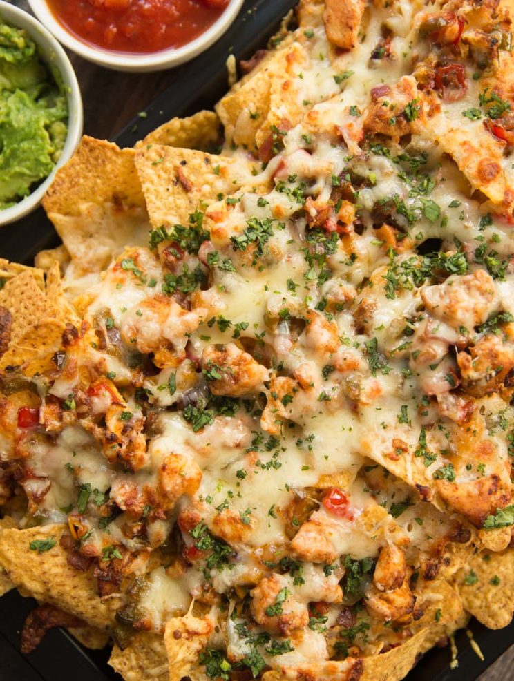 overhead shot of chicken nachos on tray garnished with coriander
