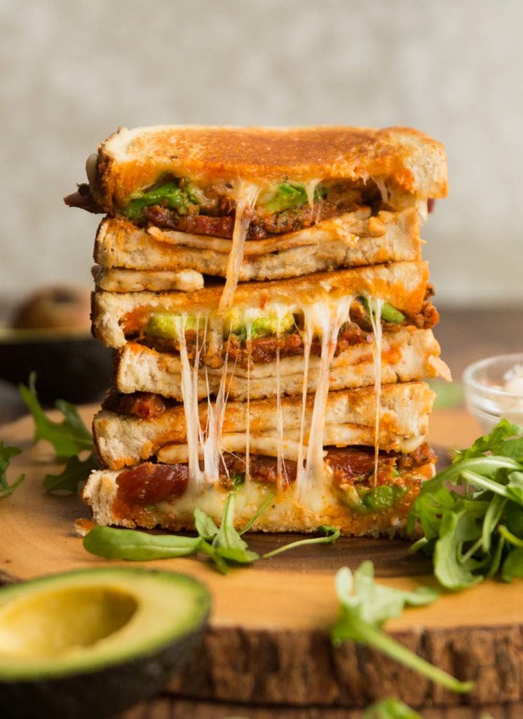 halloumi grilled cheese sandwich stacked on wooden board surrounded by rocket