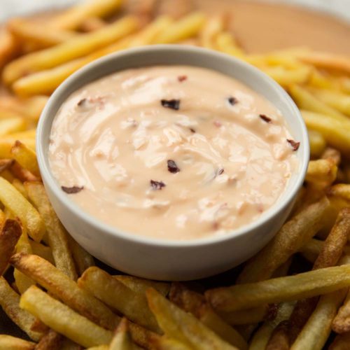 closeup shot of sweet chilli mayo in pot surrounded by fries