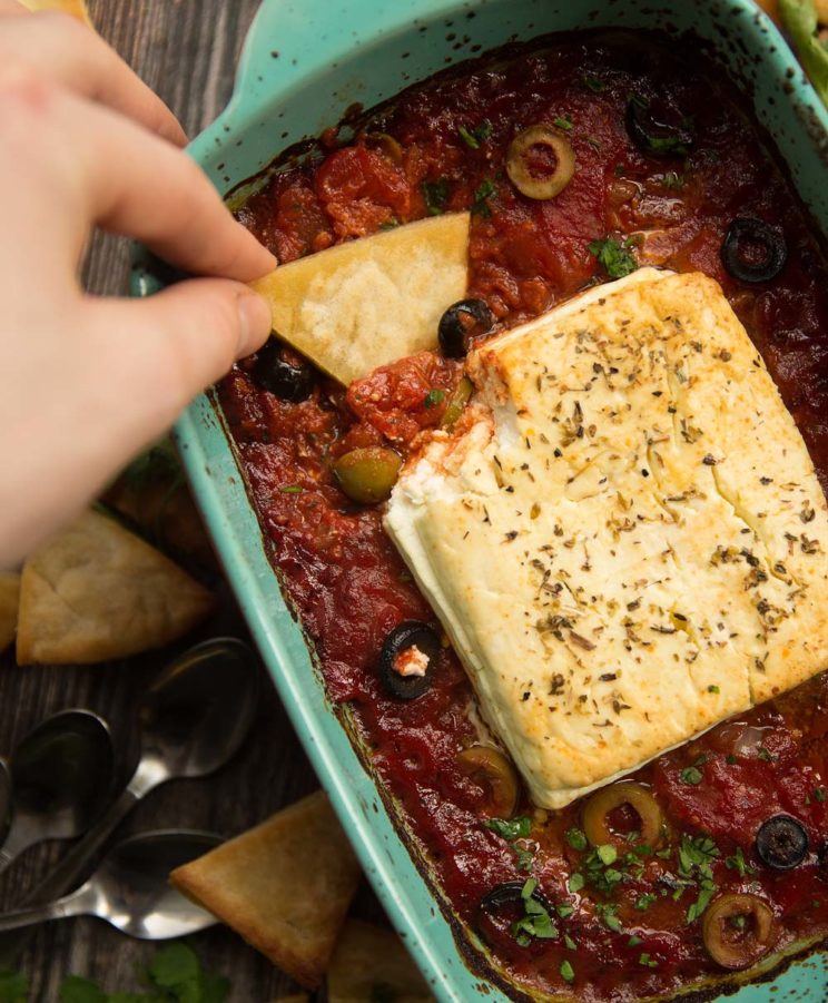 overhead shot of dunking pita chip into baked feta