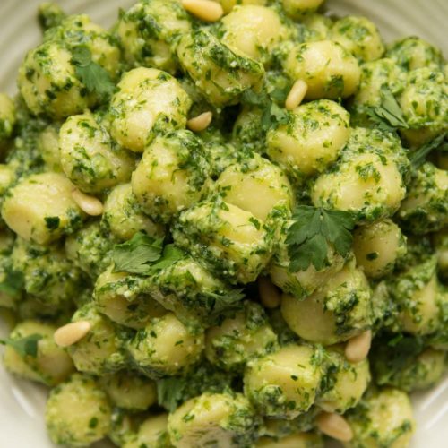 overhead shot of gnocchi pesto in white bowl