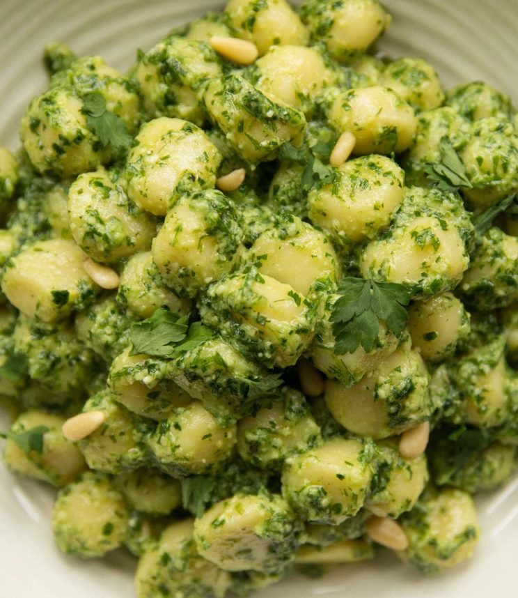 overhead shot of gnocchi pesto in white bowl