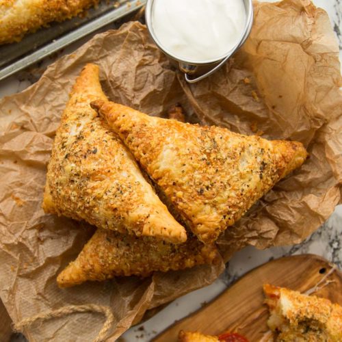 overhead shot of pizza pockets stacked on parchment paper with dip