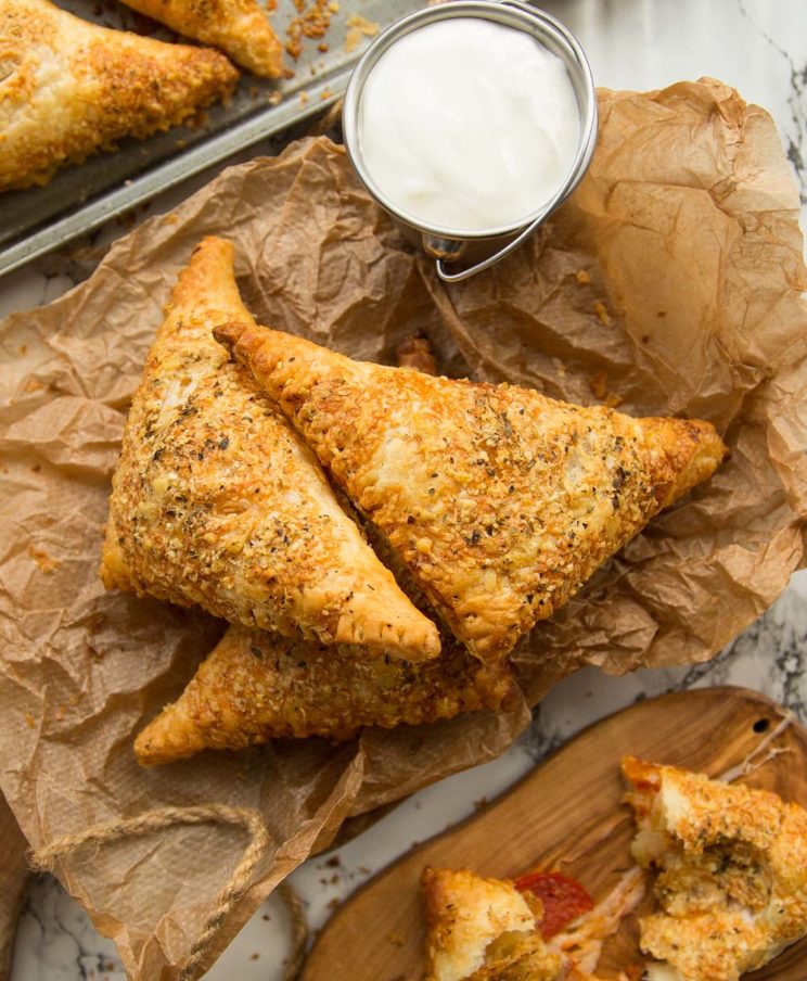 overhead shot of pizza pockets stacked on parchment paper with dip