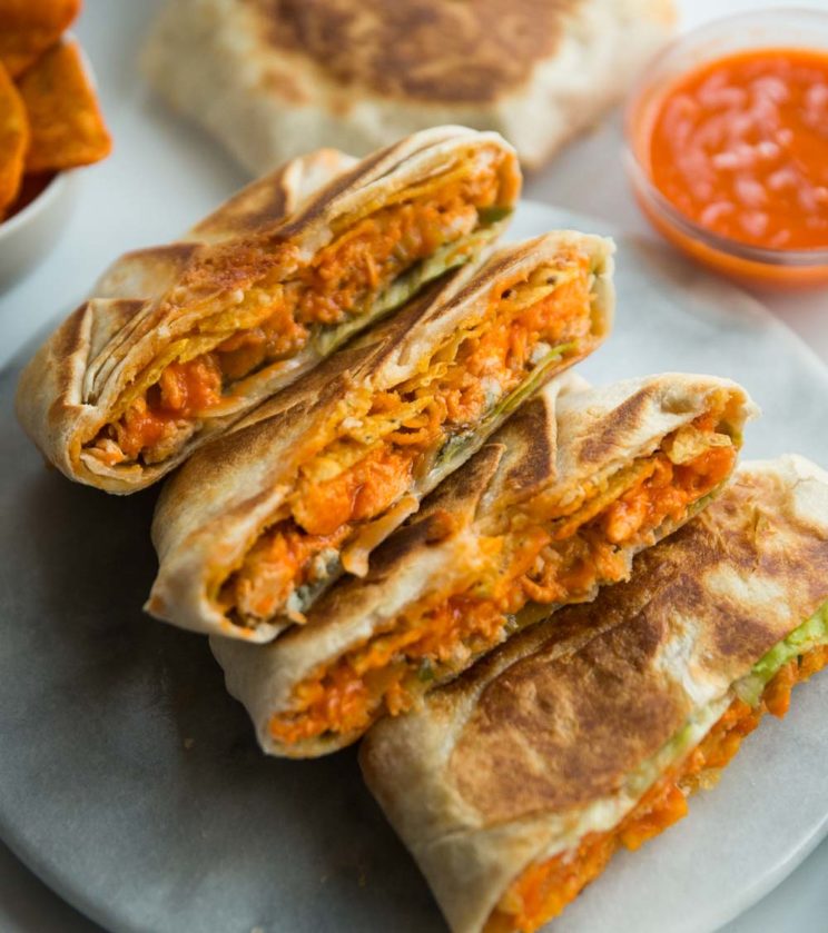crunch wraps stacked on eachother on marble board with sauce blurred in background
