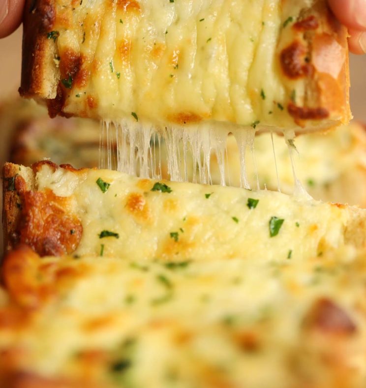 pulling garlic bread off chopping board with cheese pull