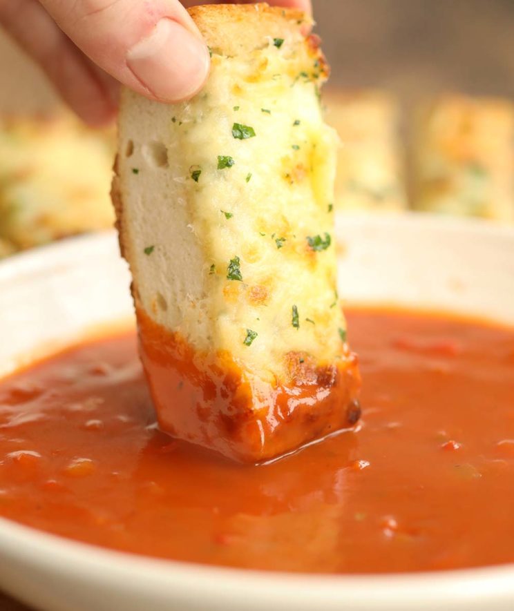 dunking cheesy garlic bread into bowl of tomato soup