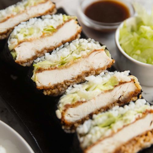 sushi sandwiches stacked on long plate with garnish surrounding