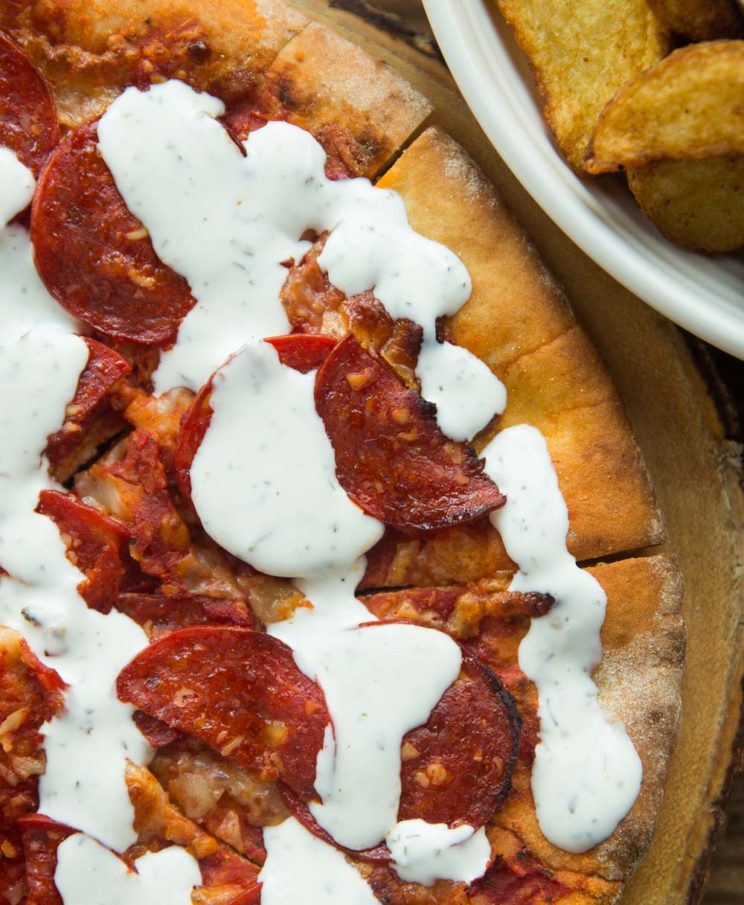 overhead shot of garlic and herb dip drizzled over pizza