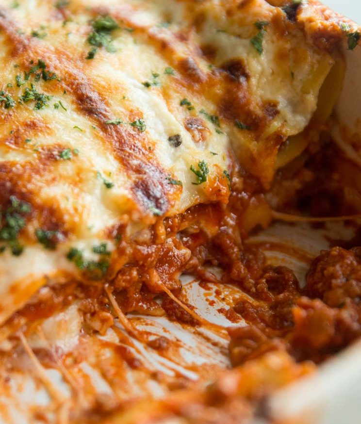 closeup shot of lasagne in dish with cheese spilling out