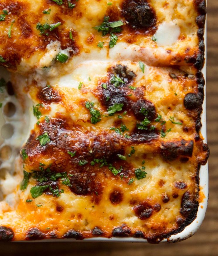 overhead shot of sausage lasagne fresh out the oven with serving spoon digging in