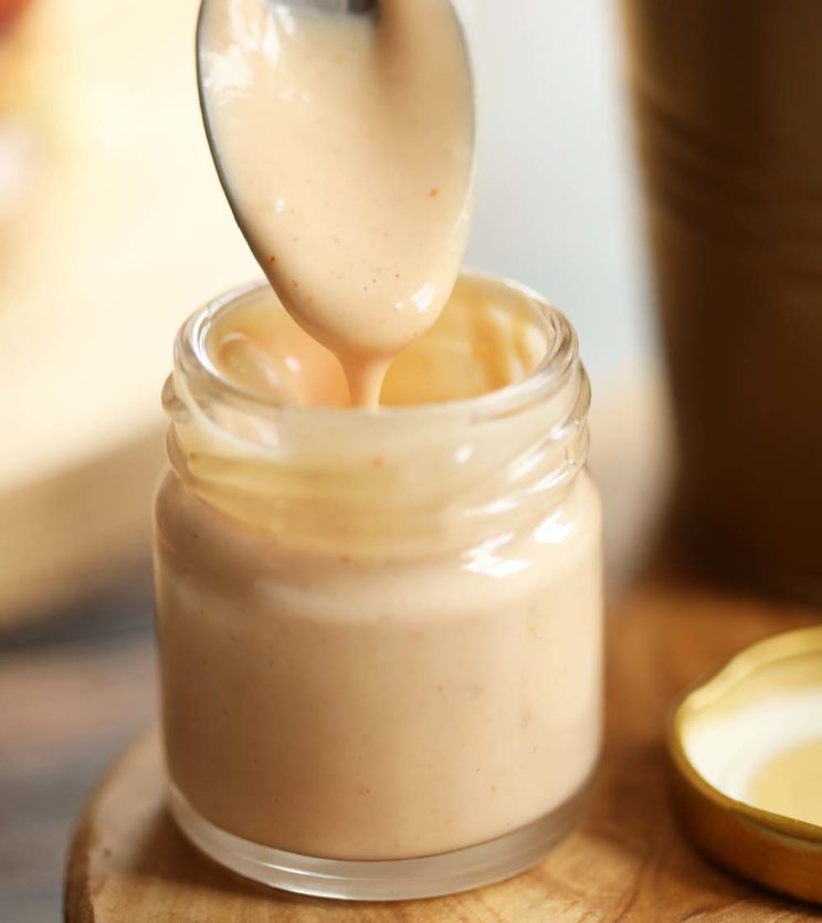 spoon dipping into small glass pot of burger sauce