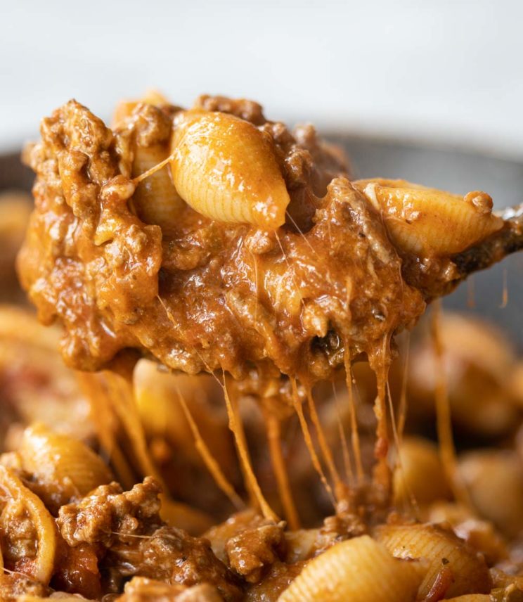 scooping pasta out of pan with cheese dripping down