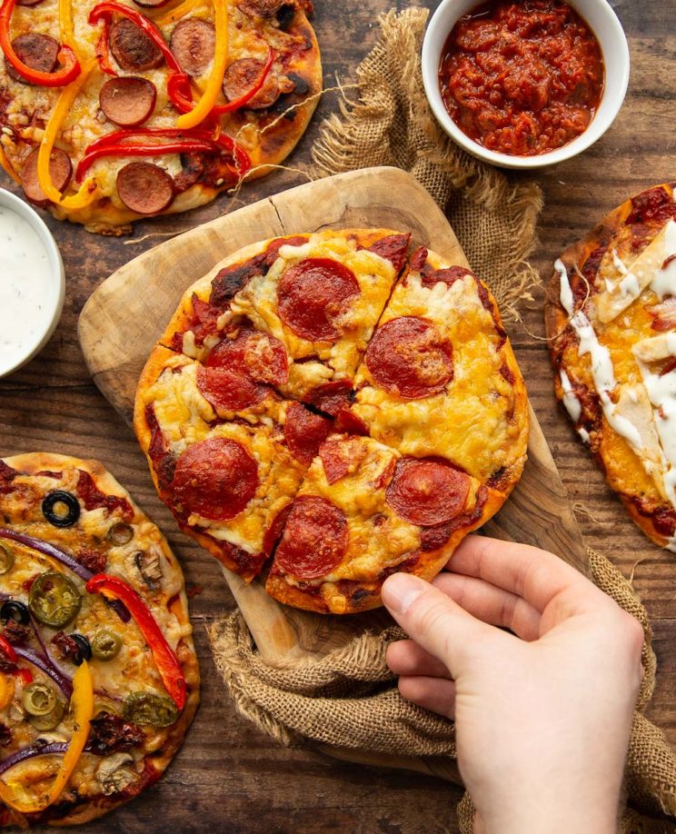 overhead shot of hand reaching to grab slice of pizza