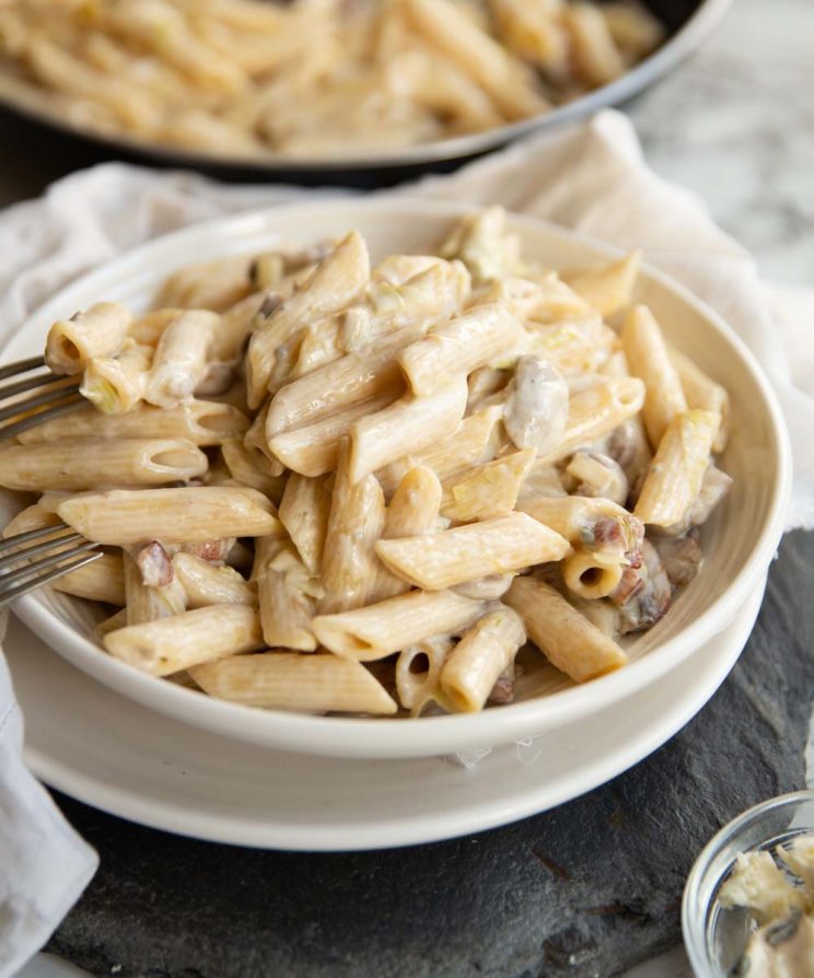 pasta plated up in a white bowl with skillet blurred in the background