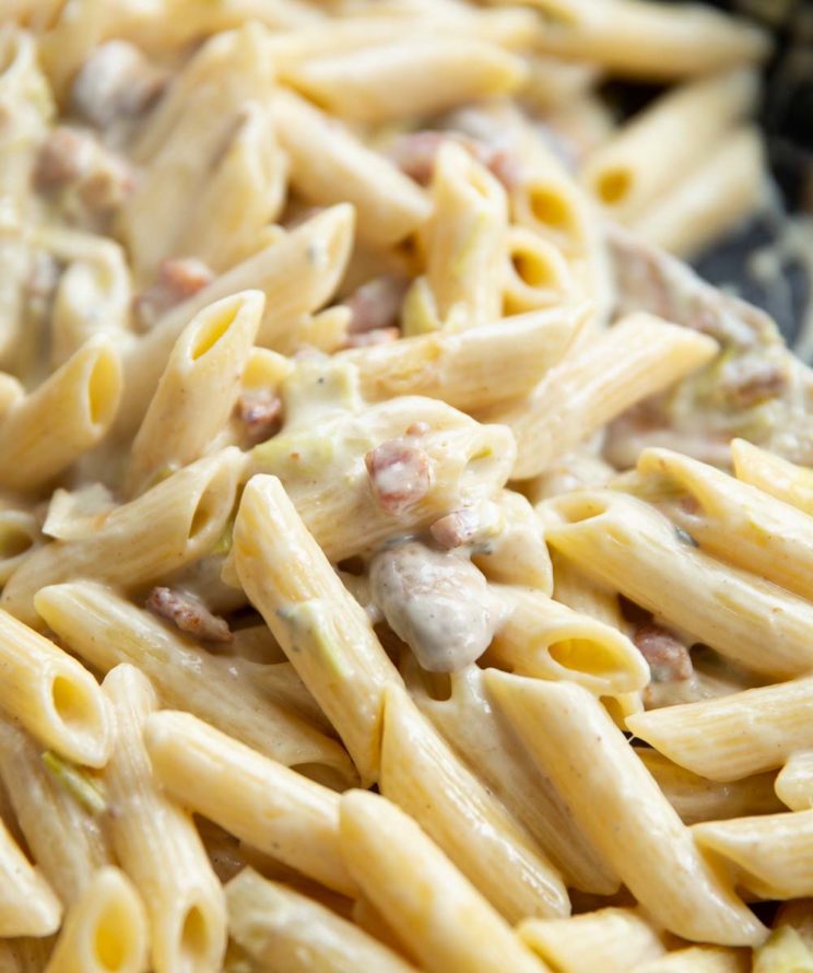 closeup shot of pasta in skillet with wooden spoon blurred in background