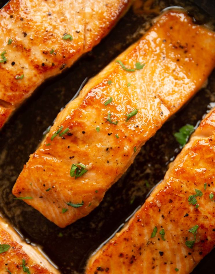 overhead shot of salmon fillets in pan garnished with parsley