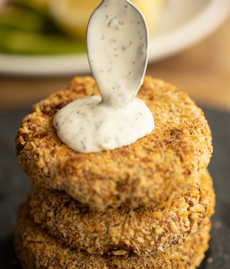 teaspoon pouring sauce onto tuna fish cakes