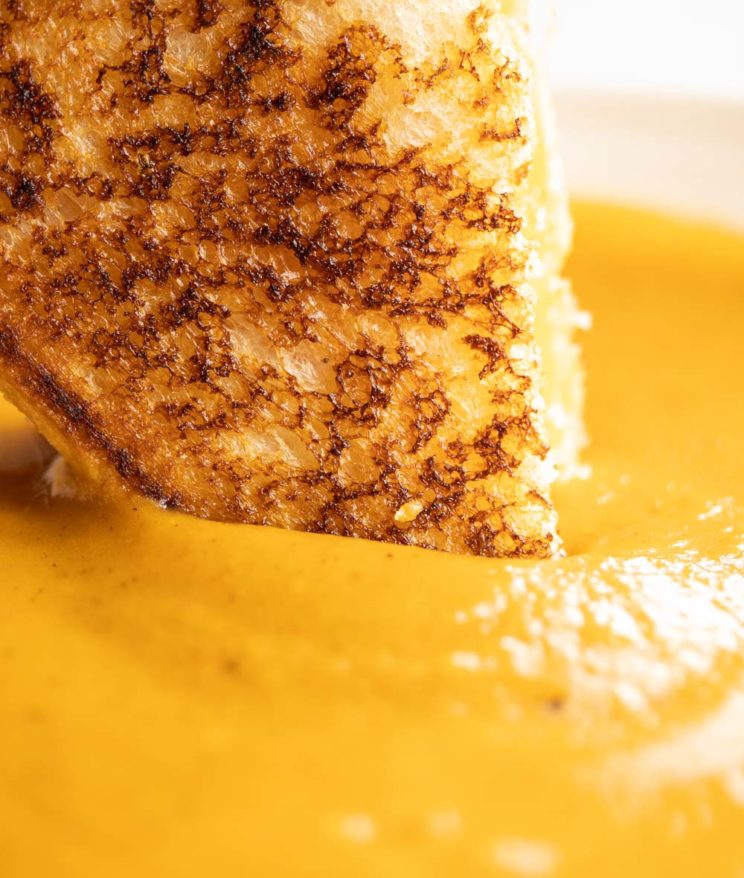 close up shot of dunking grilled cheese into soup
