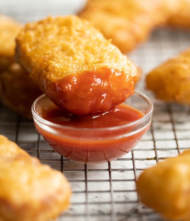 fritter resting on small glass pot of ketchup on cooling rack