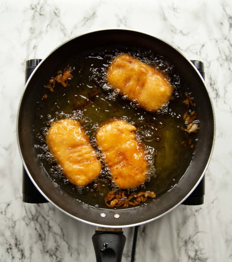 overhead shot of fritters deep frying in pot of oil