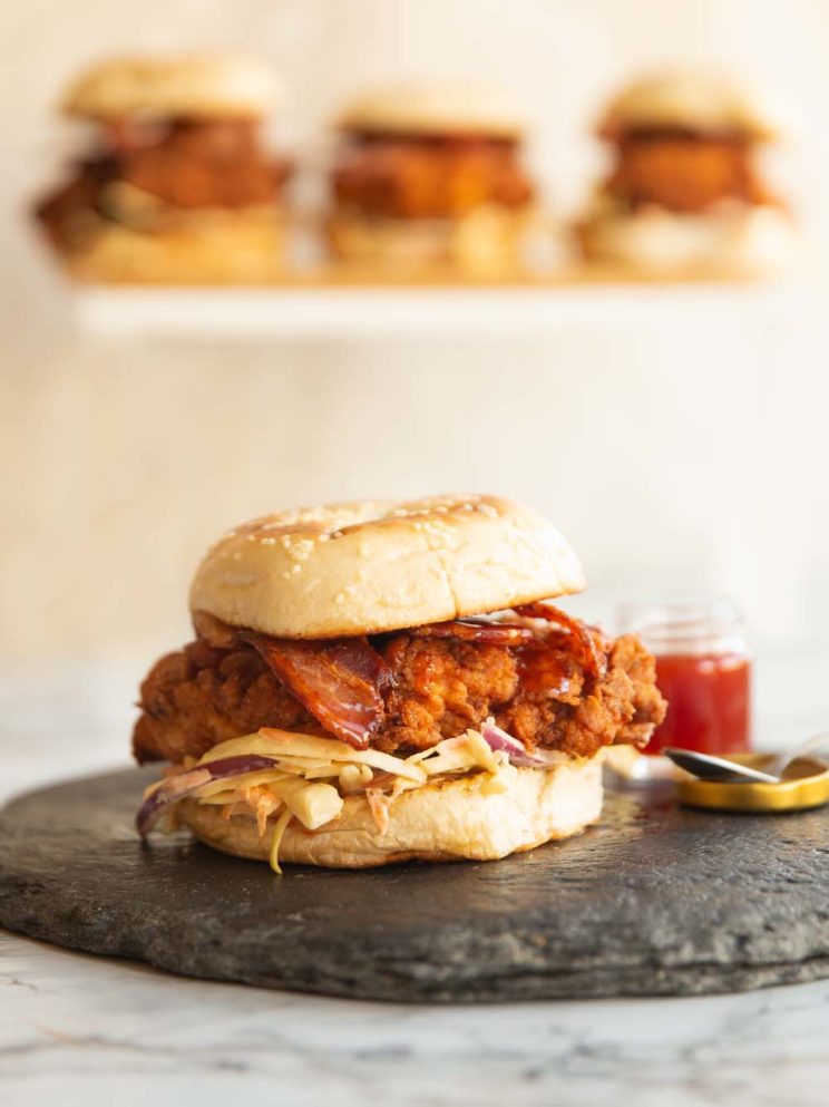 chicken burger on slate with 3 more levitated and blurred behind