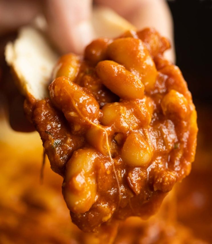 closeup of beans scooped on chunk of white bread
